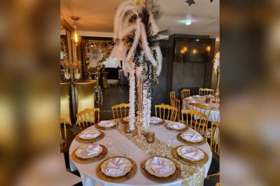 Figurines de mariés sur un gâteau décoré de fleurs bleues, d'une feuille argentée et d'un cœur en arrière-plan.
