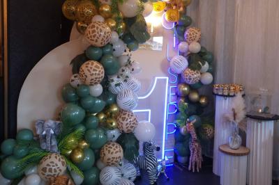 Figurines de mariés sur un gâteau décoré de fleurs bleues, d'une feuille argentée et d'un cœur en arrière-plan.