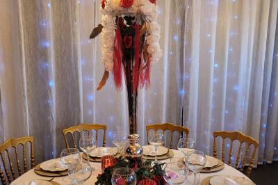 Figurines de mariés sur un gâteau décoré de fleurs bleues, d'une feuille argentée et d'un cœur en arrière-plan.