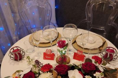 Figurines de mariés sur un gâteau décoré de fleurs bleues, d'une feuille argentée et d'un cœur en arrière-plan.