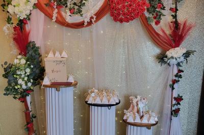 Figurines de mariés sur un gâteau décoré de fleurs bleues, d'une feuille argentée et d'un cœur en arrière-plan.