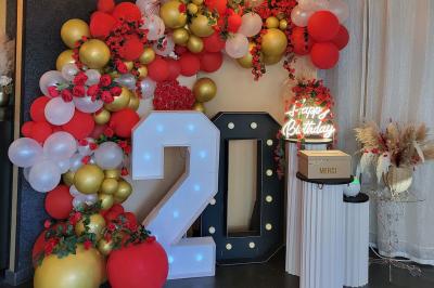 Figurines de mariés sur un gâteau décoré de fleurs bleues, d'une feuille argentée et d'un cœur en arrière-plan.