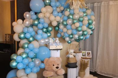 Figurines de mariés sur un gâteau décoré de fleurs bleues, d'une feuille argentée et d'un cœur en arrière-plan.