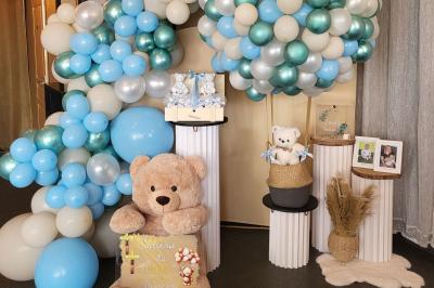 Figurines de mariés sur un gâteau décoré de fleurs bleues, d'une feuille argentée et d'un cœur en arrière-plan.