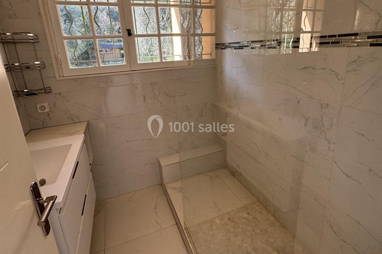 Salle de bain moderne avec douche à l'italienne, carrelage effet marbre et fenêtre à carreaux donnant sur l'extérieur.