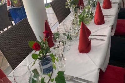 Assiette garnie d'un jarret d'agneau, légumes, pommes de terre rôties, sur une table dressée avec boissons et décorations.