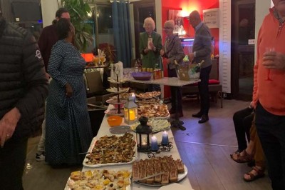 Assiette garnie d'un jarret d'agneau, légumes, pommes de terre rôties, sur une table dressée avec boissons et décorations.