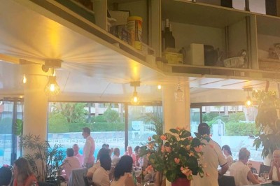 Assiette garnie d'un jarret d'agneau, légumes, pommes de terre rôties, sur une table dressée avec boissons et décorations.