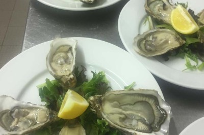 Assiette garnie d'un jarret d'agneau, légumes, pommes de terre rôties, sur une table dressée avec boissons et décorations.