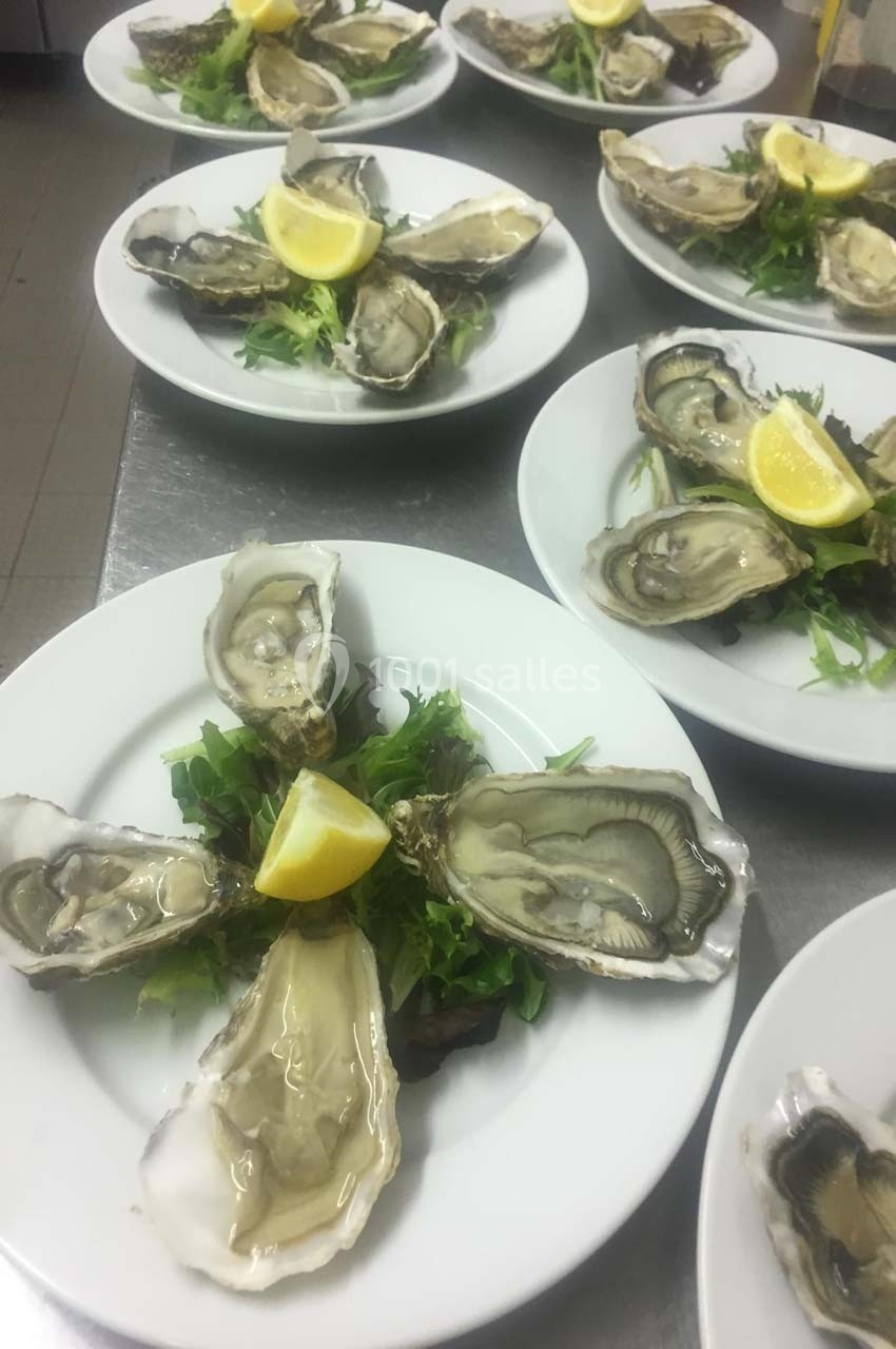 Assiettes d'huîtres ouvertes servies sur un lit de salade avec un quartier de citron au centre.