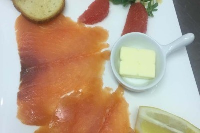 Assiette garnie d'un jarret d'agneau, légumes, pommes de terre rôties, sur une table dressée avec boissons et décorations.