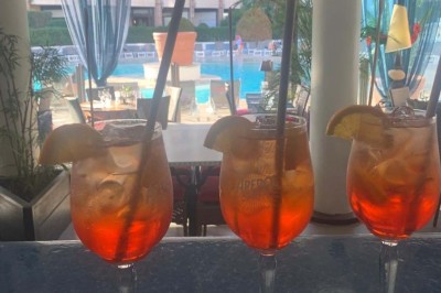 Assiette garnie d'un jarret d'agneau, légumes, pommes de terre rôties, sur une table dressée avec boissons et décorations.