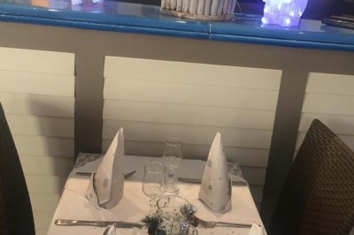 Assiette garnie d'un jarret d'agneau, légumes, pommes de terre rôties, sur une table dressée avec boissons et décorations.