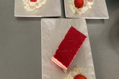 Assiette garnie d'un jarret d'agneau, légumes, pommes de terre rôties, sur une table dressée avec boissons et décorations.