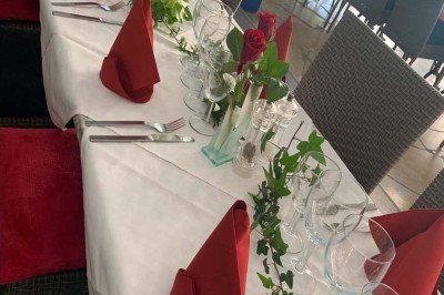 Assiette garnie d'un jarret d'agneau, légumes, pommes de terre rôties, sur une table dressée avec boissons et décorations.