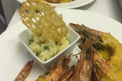 Assiette garnie d'un jarret d'agneau, légumes, pommes de terre rôties, sur une table dressée avec boissons et décorations.