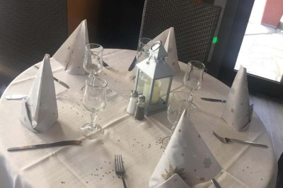 Assiette garnie d'un jarret d'agneau, légumes, pommes de terre rôties, sur une table dressée avec boissons et décorations.