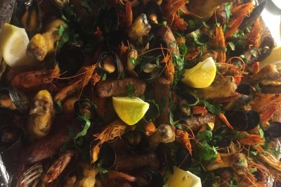 Assiette garnie d'un jarret d'agneau, légumes, pommes de terre rôties, sur une table dressée avec boissons et décorations.