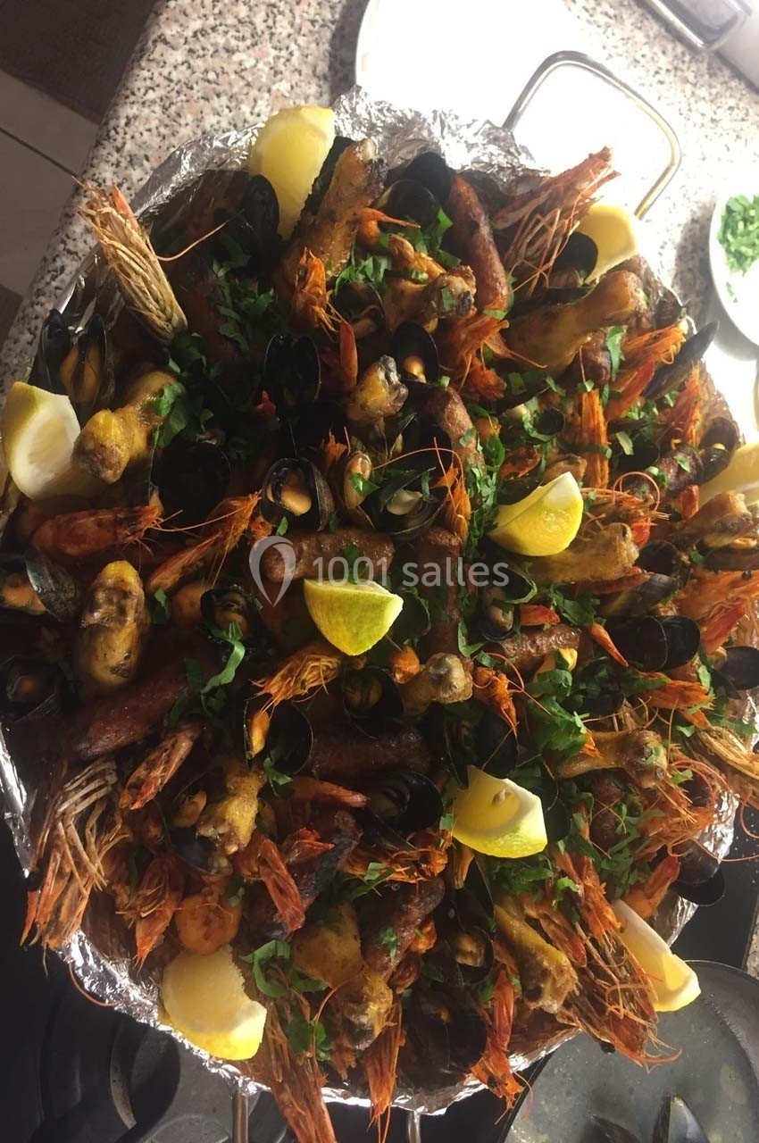 Plat de fruits de mer variés avec crevettes, moules, citron et herbes fraîches, présenté sur un plateau argenté.