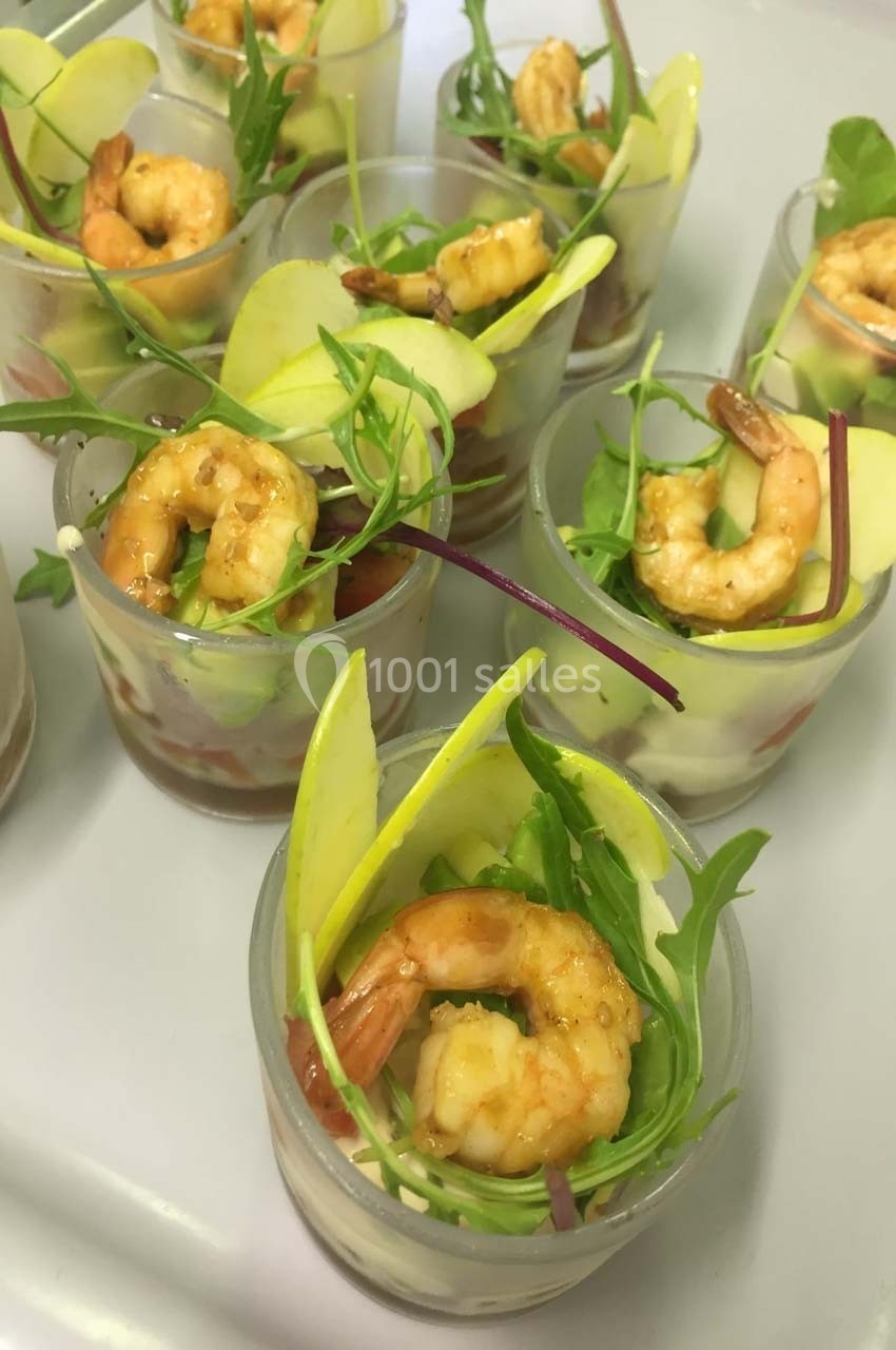 Verrines garnies de crevettes, tranches de pomme verte, roquette et pousses, présentées sur un plateau.