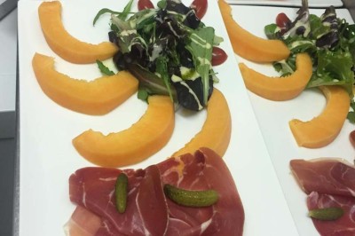 Assiette garnie d'un jarret d'agneau, légumes, pommes de terre rôties, sur une table dressée avec boissons et décorations.
