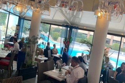 Assiette garnie d'un jarret d'agneau, légumes, pommes de terre rôties, sur une table dressée avec boissons et décorations.