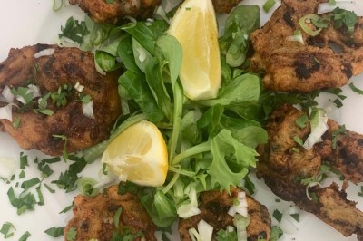 Assiette garnie d'un jarret d'agneau, légumes, pommes de terre rôties, sur une table dressée avec boissons et décorations.