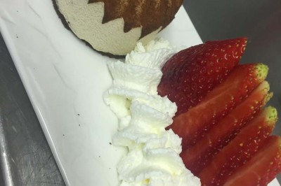 Assiette garnie d'un jarret d'agneau, légumes, pommes de terre rôties, sur une table dressée avec boissons et décorations.