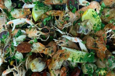 Assiette garnie d'un jarret d'agneau, légumes, pommes de terre rôties, sur une table dressée avec boissons et décorations.