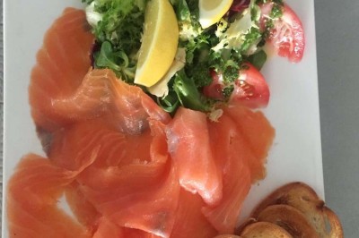 Assiette garnie d'un jarret d'agneau, légumes, pommes de terre rôties, sur une table dressée avec boissons et décorations.