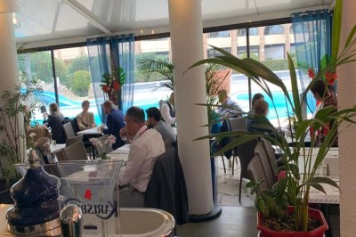 Assiette garnie d'un jarret d'agneau, légumes, pommes de terre rôties, sur une table dressée avec boissons et décorations.