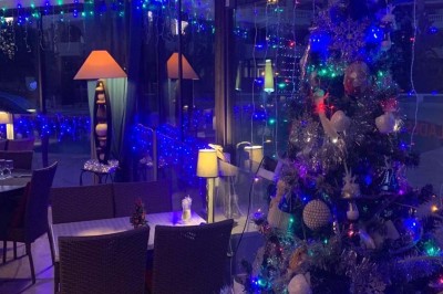 Assiette garnie d'un jarret d'agneau, légumes, pommes de terre rôties, sur une table dressée avec boissons et décorations.