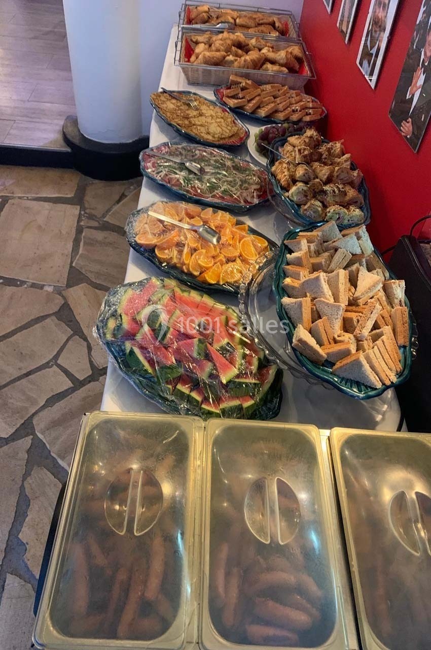 Buffet varié avec fruits, légumes, sandwichs, viennoiseries et plats chauds disposés sur une table.