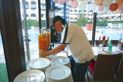 Assiette garnie d'un jarret d'agneau, légumes, pommes de terre rôties, sur une table dressée avec boissons et décorations.