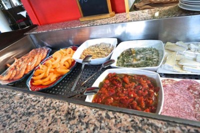Assiette garnie d'un jarret d'agneau, légumes, pommes de terre rôties, sur une table dressée avec boissons et décorations.