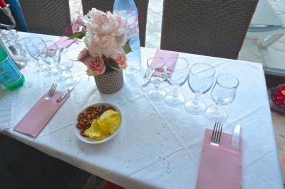 Assiette garnie d'un jarret d'agneau, légumes, pommes de terre rôties, sur une table dressée avec boissons et décorations.