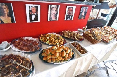 Assiette garnie d'un jarret d'agneau, légumes, pommes de terre rôties, sur une table dressée avec boissons et décorations.
