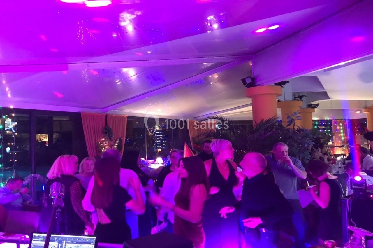 Groupe de personnes dansant sous des lumières colorées dans une salle décorée pour une soirée festive.