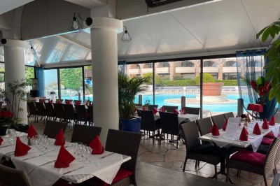 Assiette garnie d'un jarret d'agneau, légumes, pommes de terre rôties, sur une table dressée avec boissons et décorations.