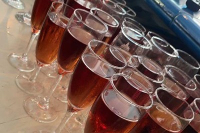 Assiette garnie d'un jarret d'agneau, légumes, pommes de terre rôties, sur une table dressée avec boissons et décorations.