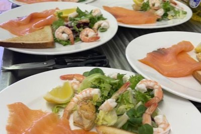 Assiette garnie d'un jarret d'agneau, légumes, pommes de terre rôties, sur une table dressée avec boissons et décorations.
