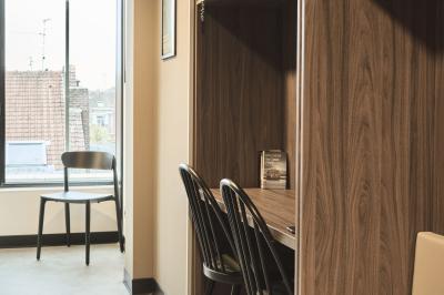Lavabo moderne avec miroir, distributeur de savon mural et carrelage beige dans une salle de bain.