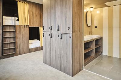 Lavabo moderne avec miroir, distributeur de savon mural et carrelage beige dans une salle de bain.