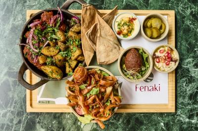 Lavabo moderne avec miroir, distributeur de savon mural et carrelage beige dans une salle de bain.