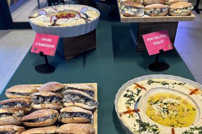 Lavabo moderne avec miroir, distributeur de savon mural et carrelage beige dans une salle de bain.