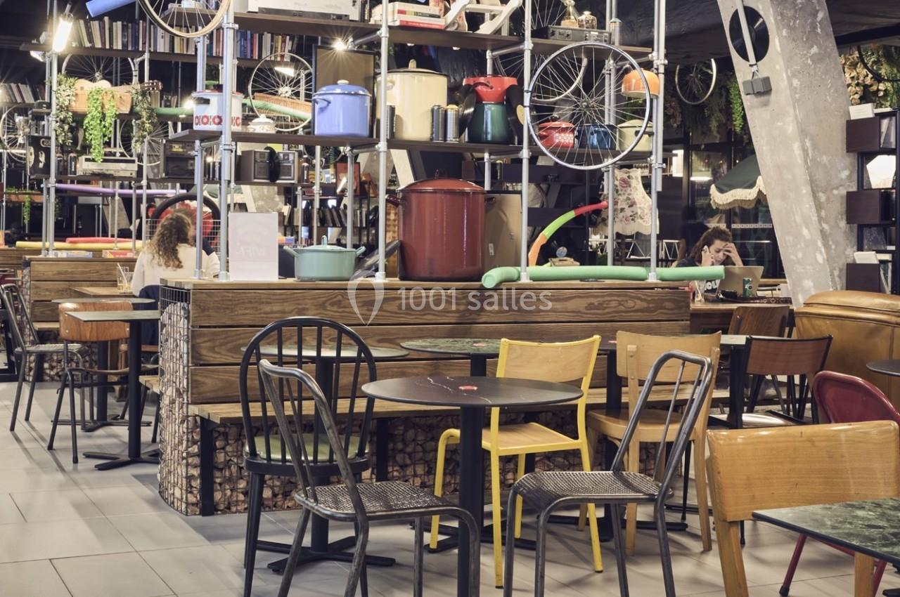 Salle de restaurant éclectique avec mobilier dépareillé, étagères décoratives et ambiance chaleureuse.