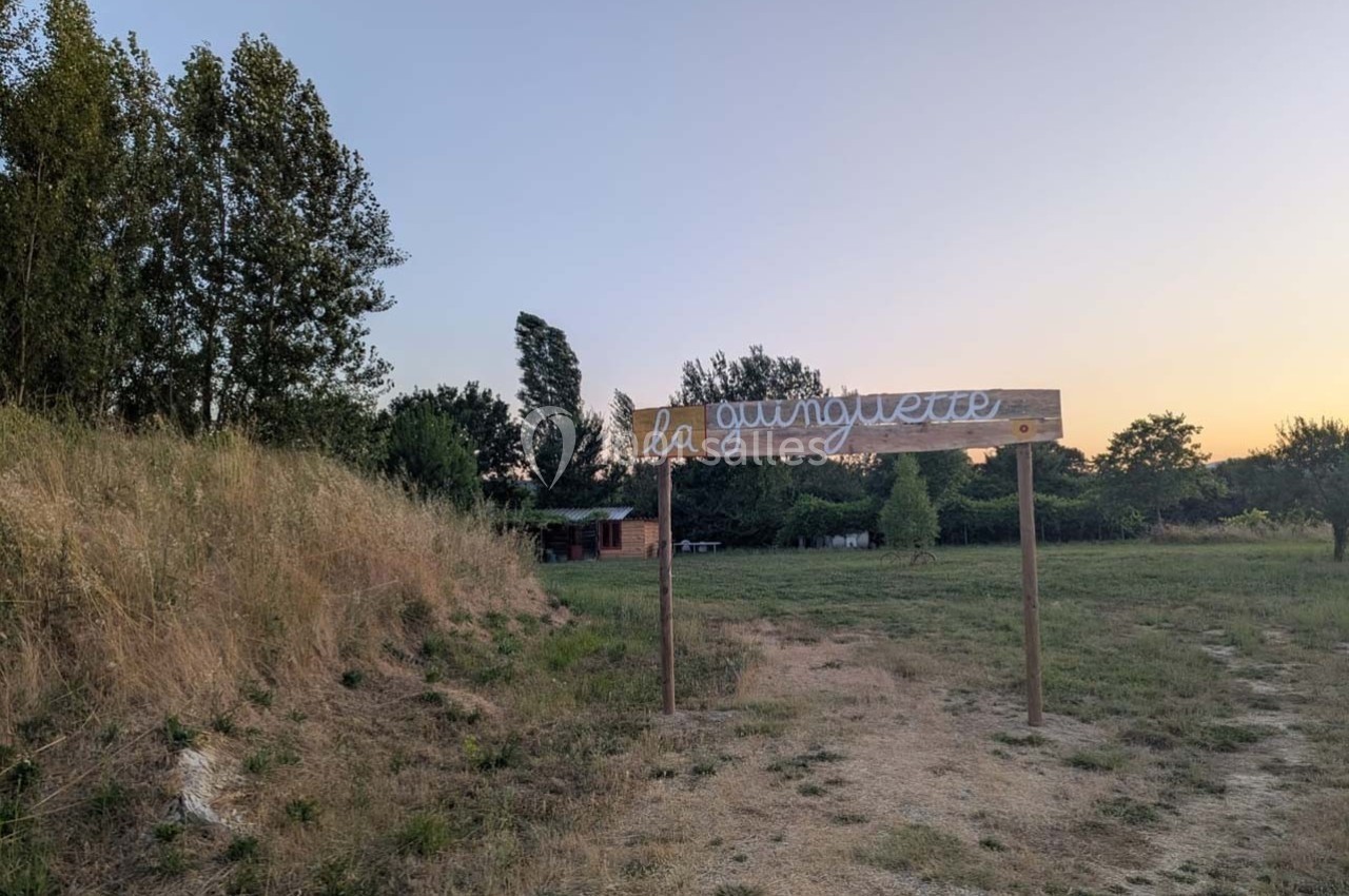Panneau en bois indiquant ’la guinguette’ dans un paysage champêtre au coucher du soleil.