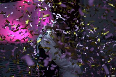 Salle de réception décorée pour un événement, avec tables rondes dressées, nappes blanches et éléments végétaux.