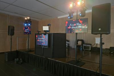 Salle de réception décorée pour un événement, avec tables rondes dressées, nappes blanches et éléments végétaux.