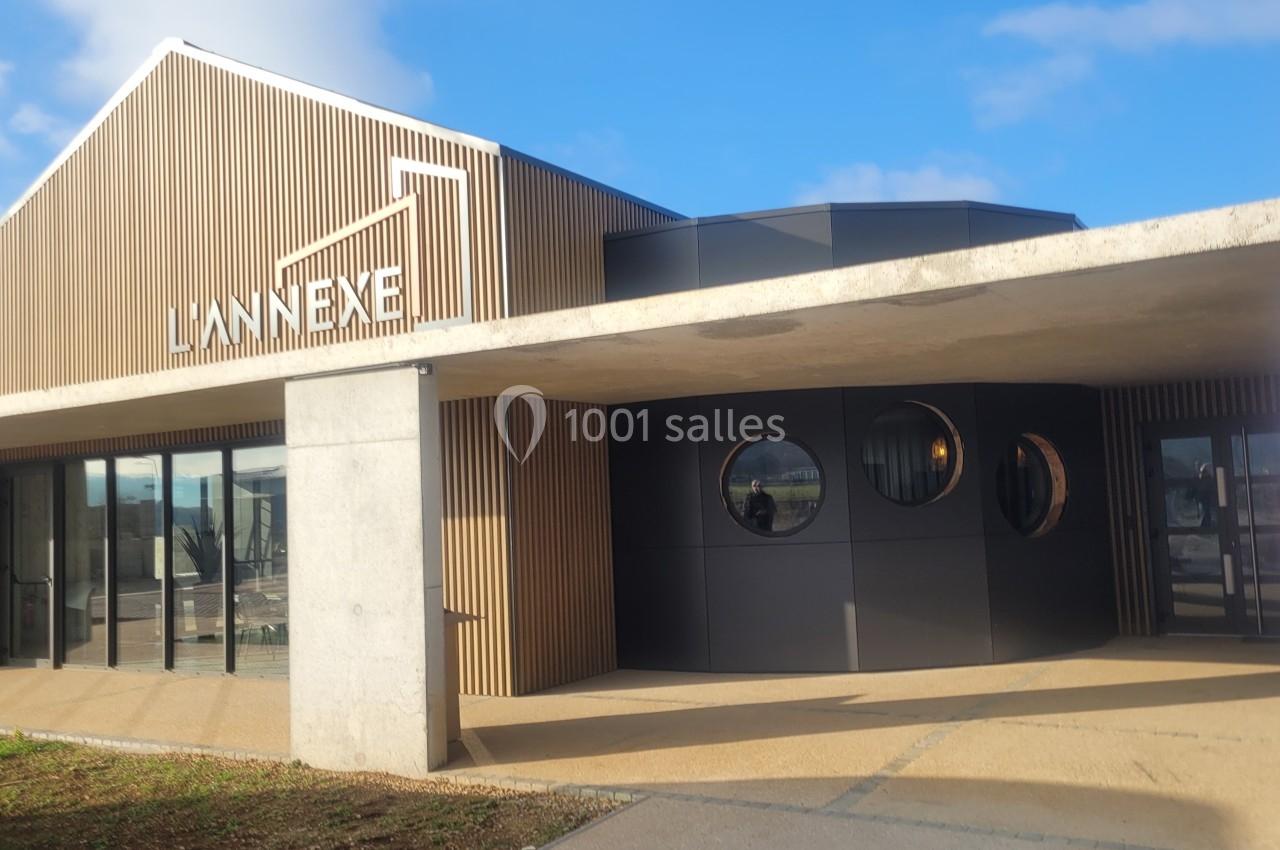 Façade moderne d'un bâtiment en bois et béton avec des fenêtres rondes et une enseigne ’L'Annexe’.